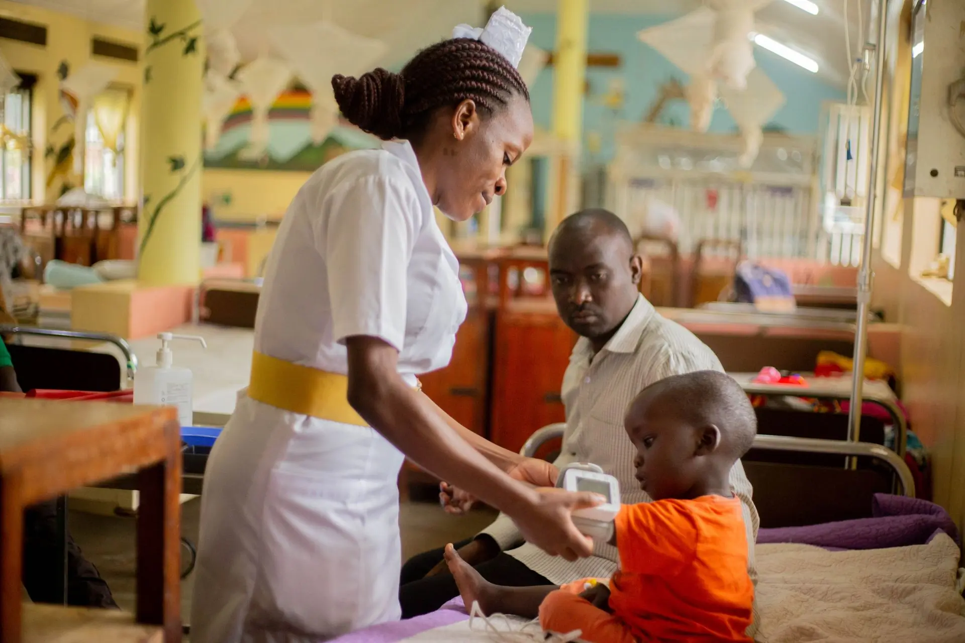 A nurse with a child and their father on the paediatric ward