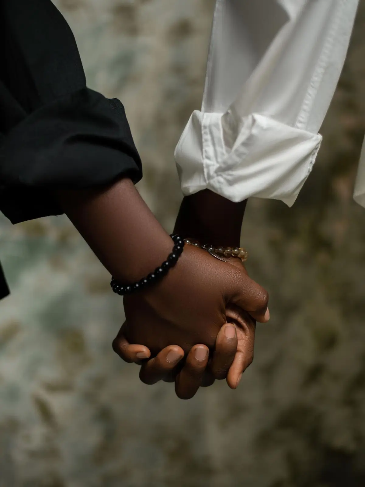 Two people holding hands, one supporting the other