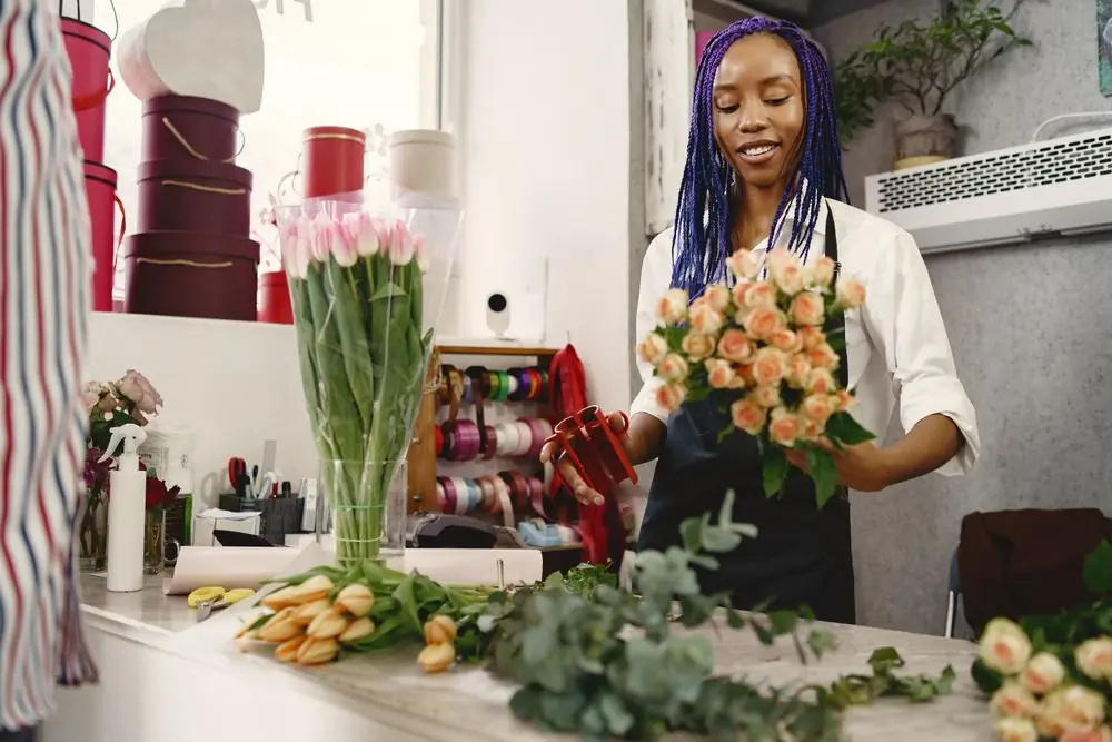 A florist arranging a bouquet of roses at a studio bench