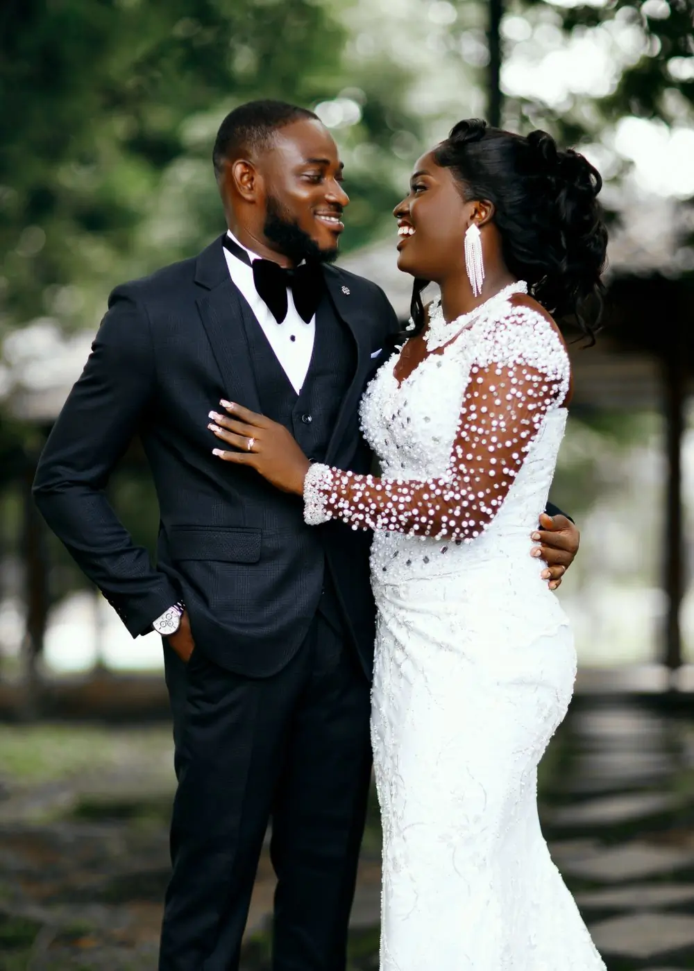 A couple outdoors in a black dinner suit and a beaded white dress