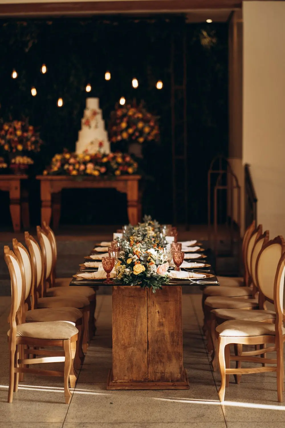 A candlelit reception room with a long table and autumn flowers