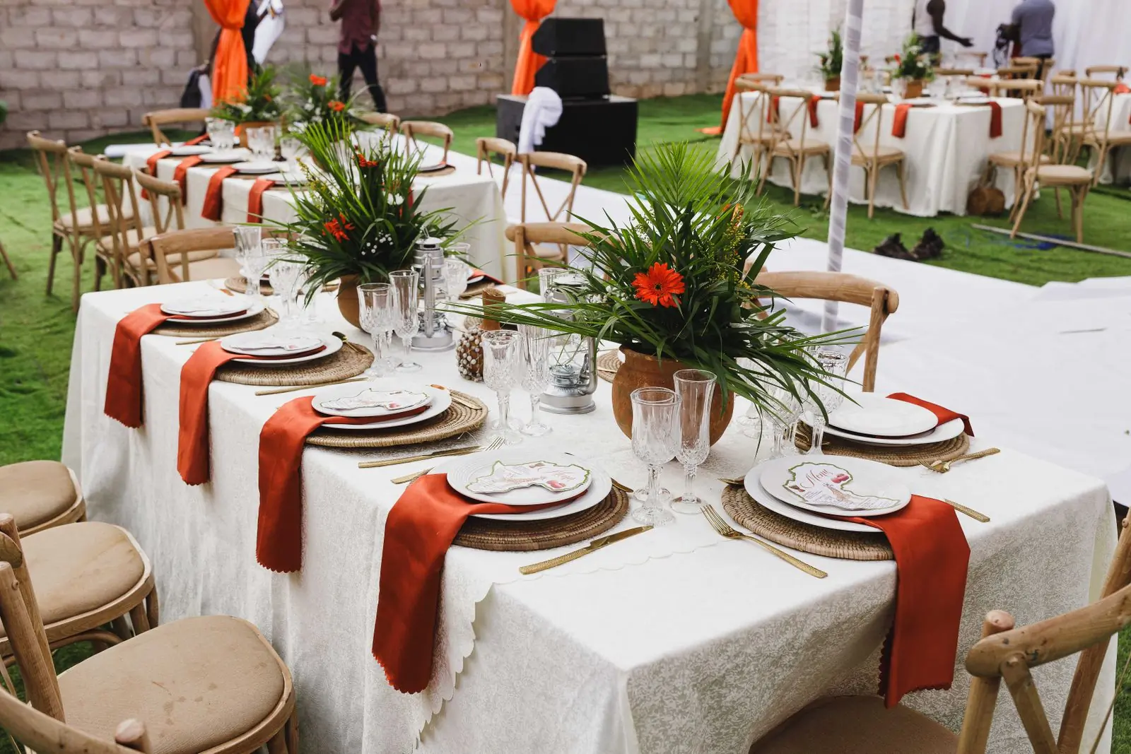 A long outdoor table dressed with terracotta napkins and greenery