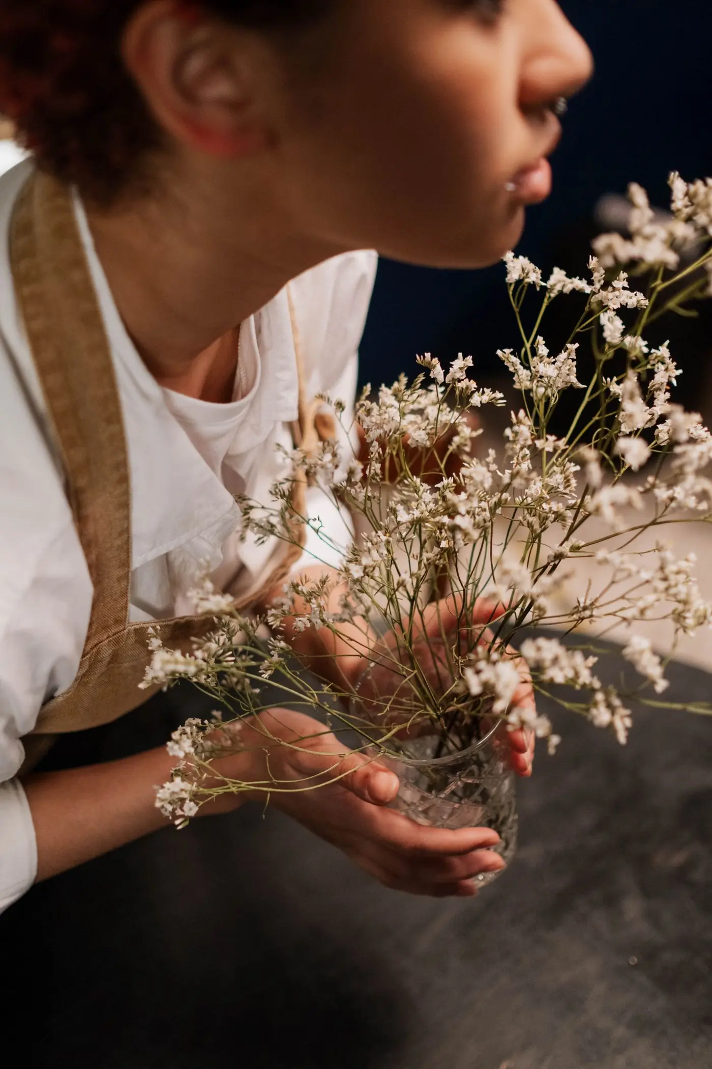 A florist holding a glass vase of dried baby's breath