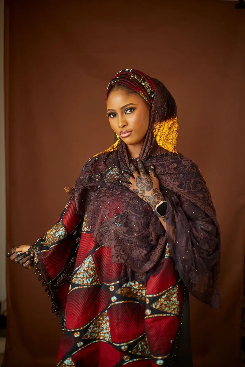 A woman in a deep red robe with an embroidered shawl over one shoulder