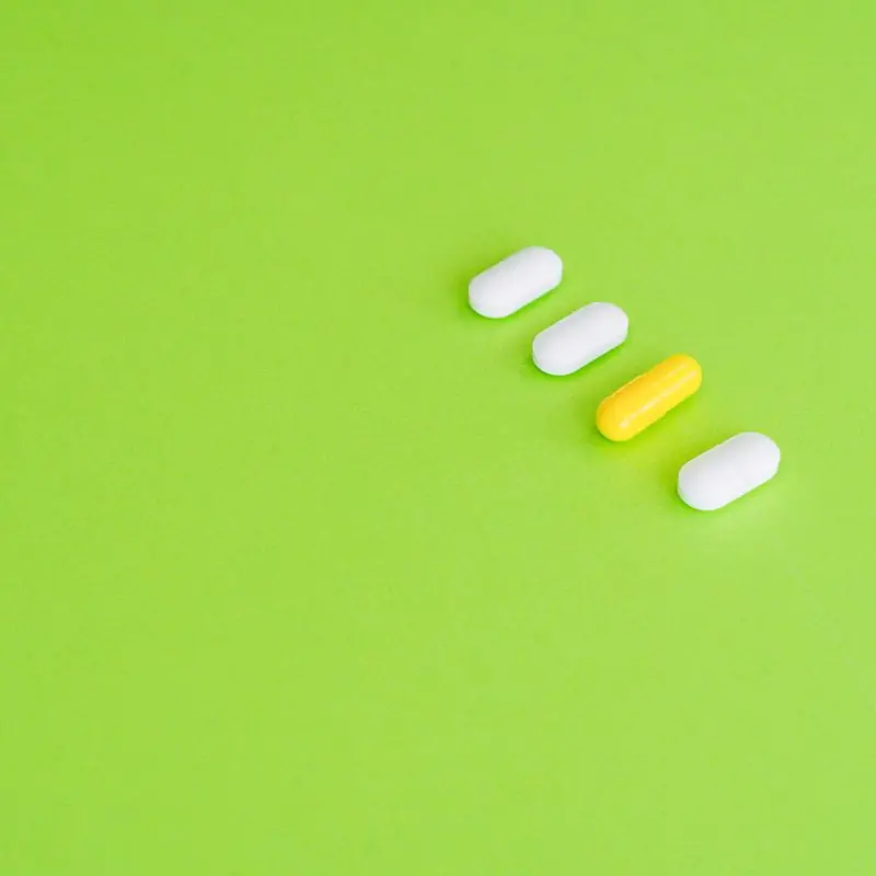 Four white and yellow tablets lined up diagonally on a bright lime green background
