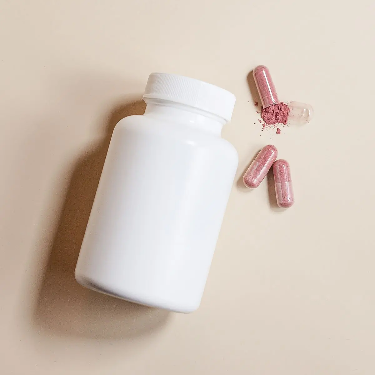 An overhead packshot of the Gut Balance bottle on beige with capsules arranged beside it