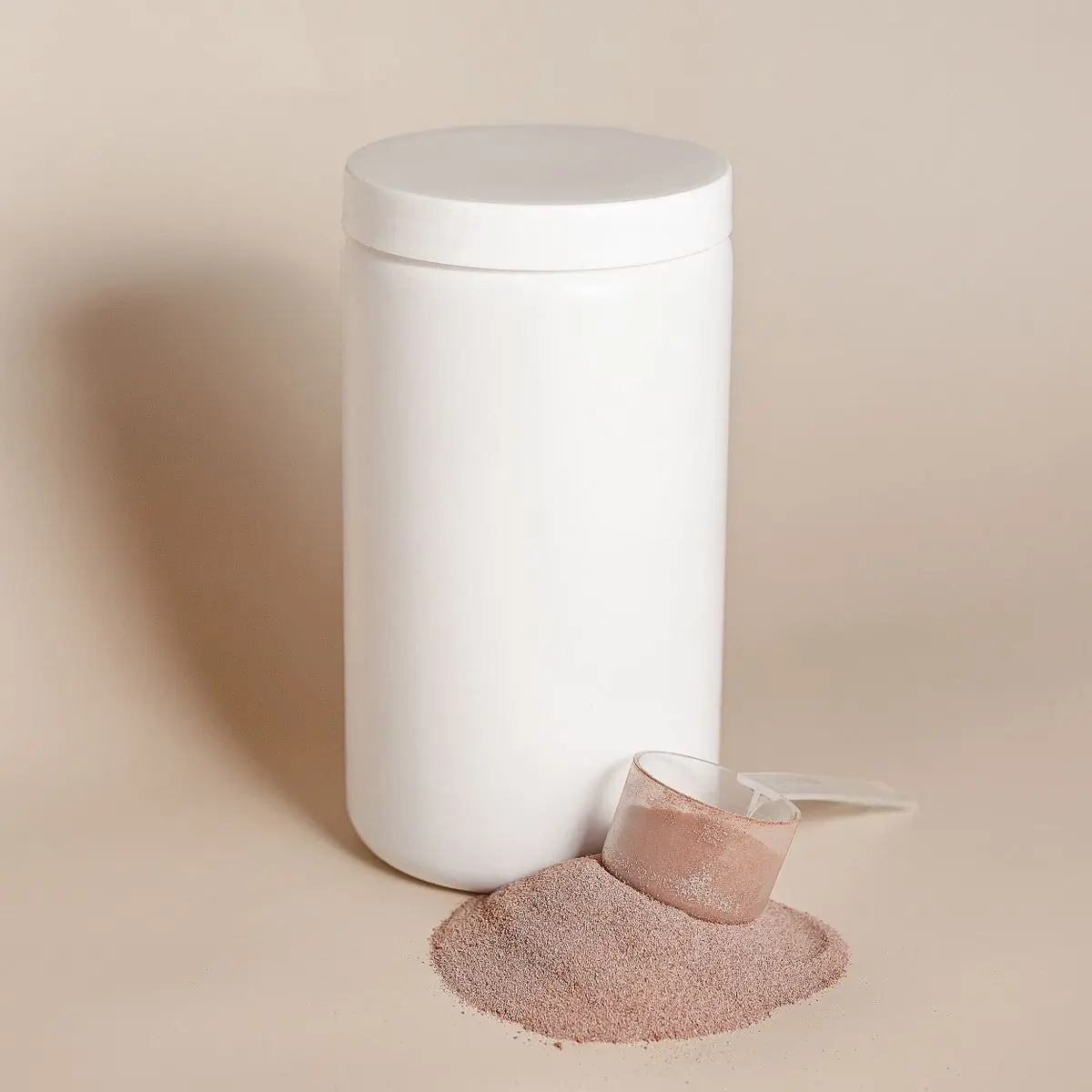 A tall white powder tub on a beige ground with a scoop of collagen powder spilled beside it