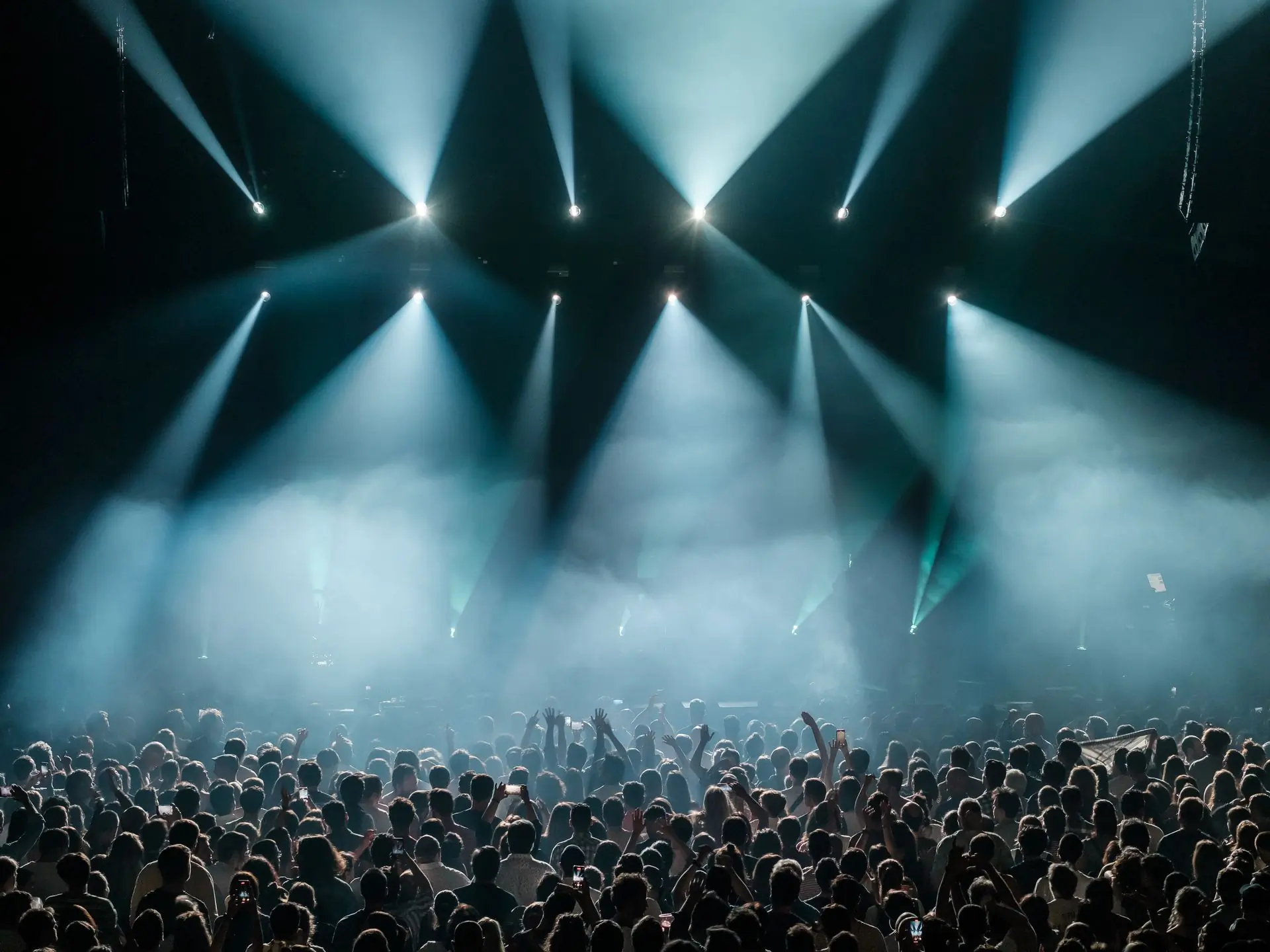 Beams of stage light over a dense night crowd