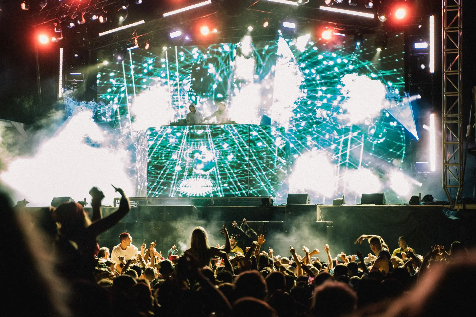 Green laser fans over a packed concert floor