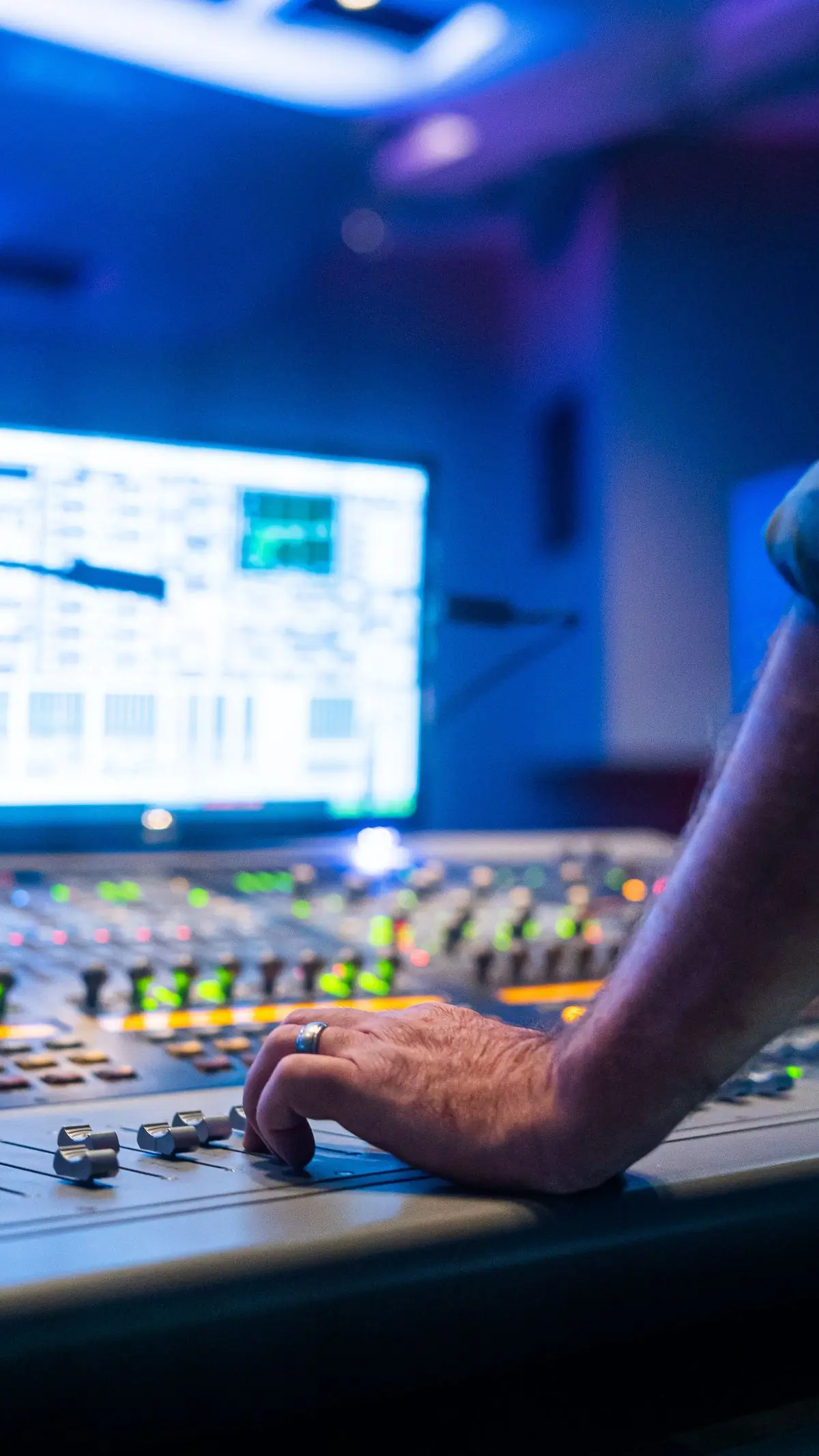 A sound engineer at a lit control desk during a live event