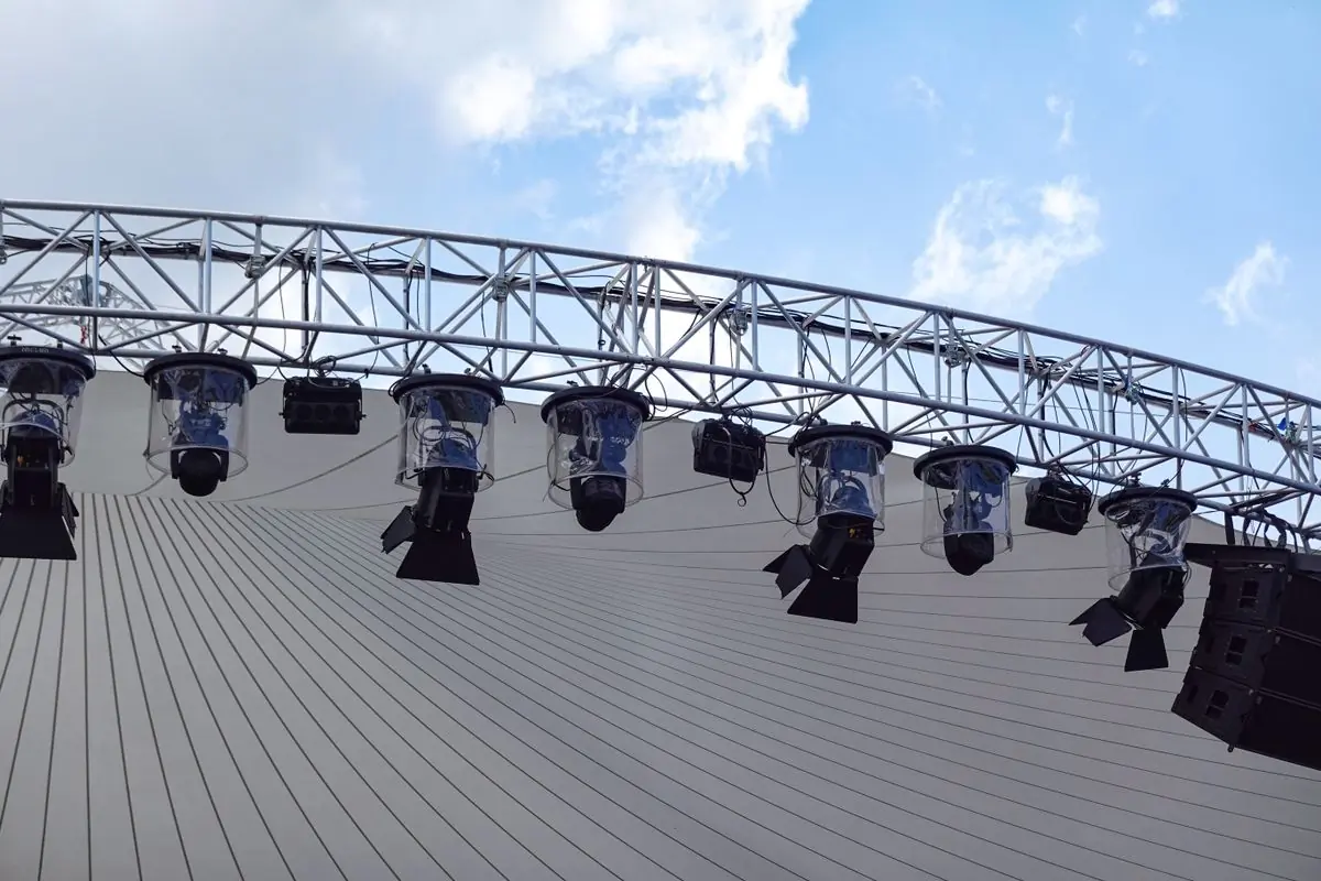 An overhead lighting rig on a truss against a clear sky