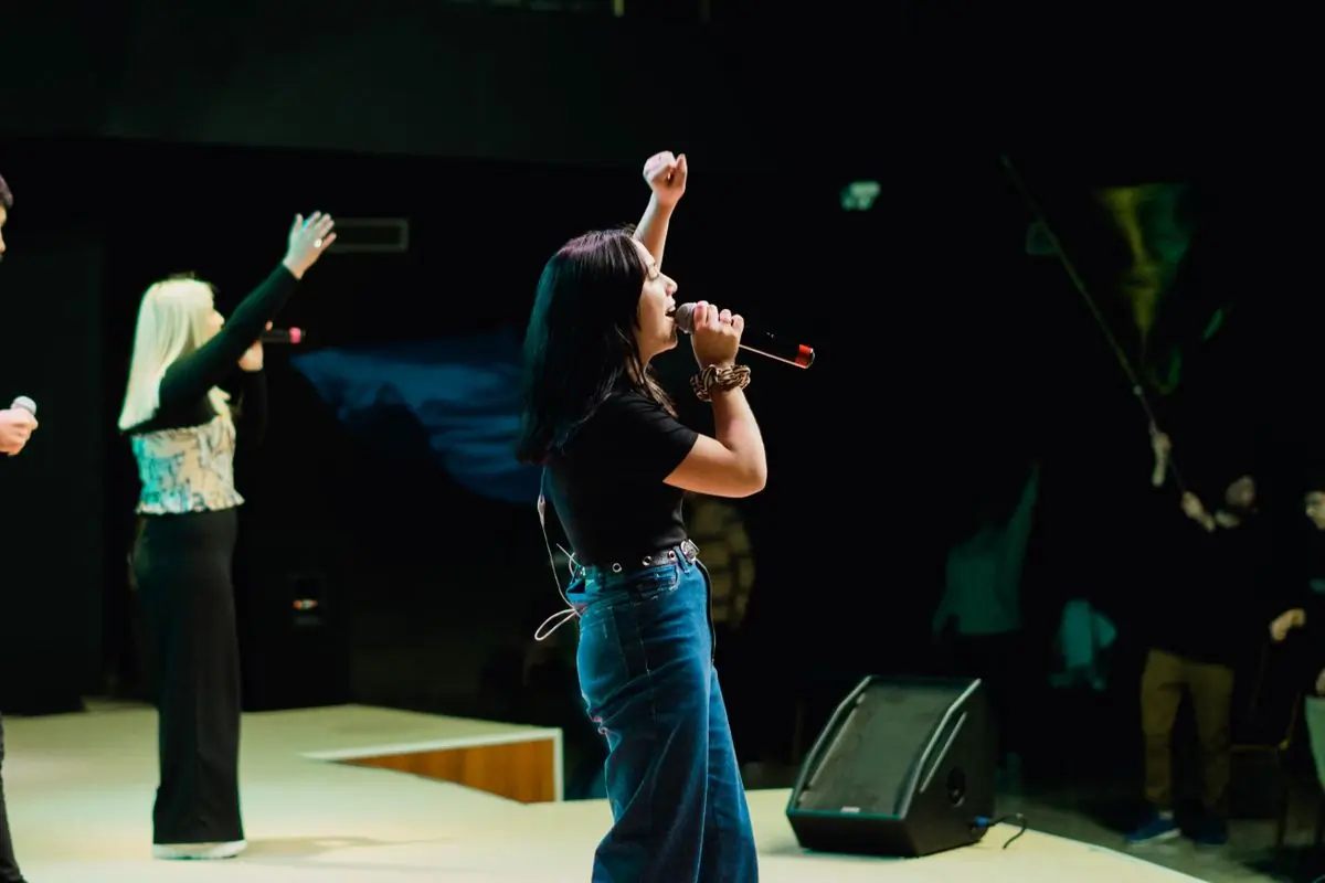 A singer performing on a brightly lit stage with a band behind her