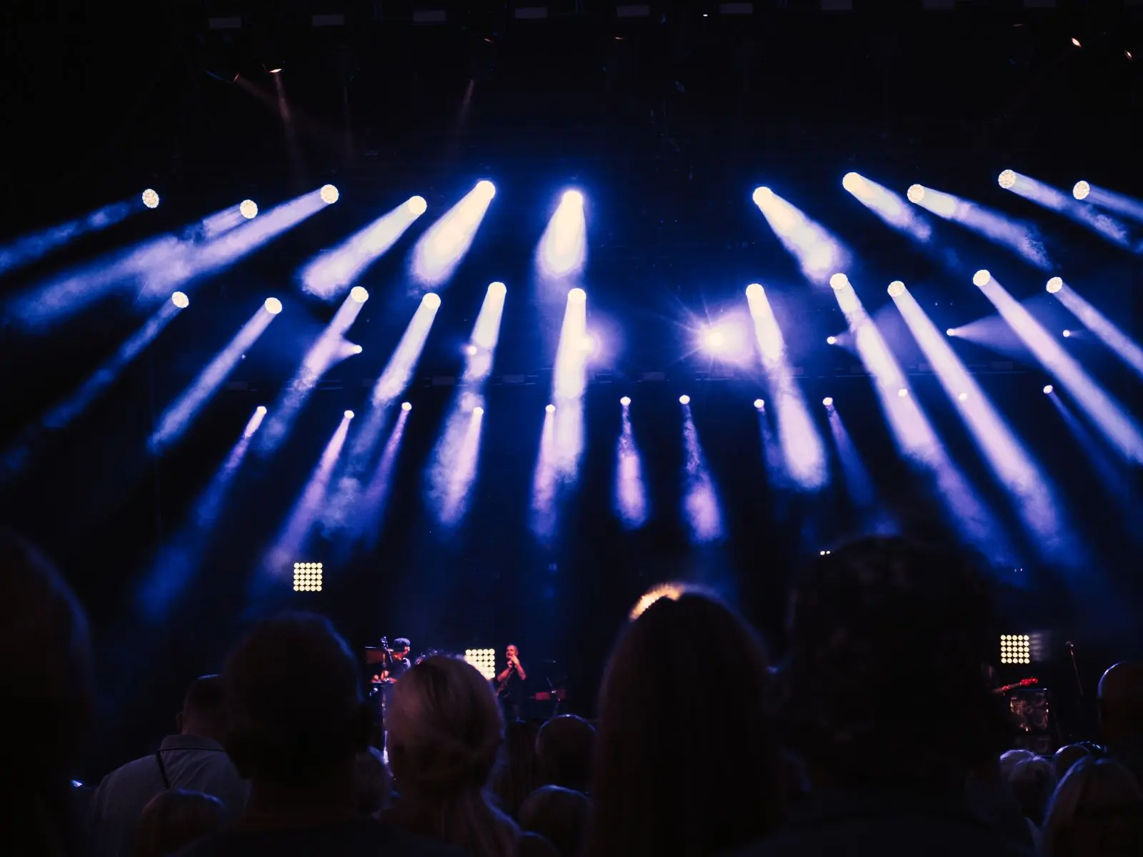 A crowd at a night concert lit in blue from the stage
