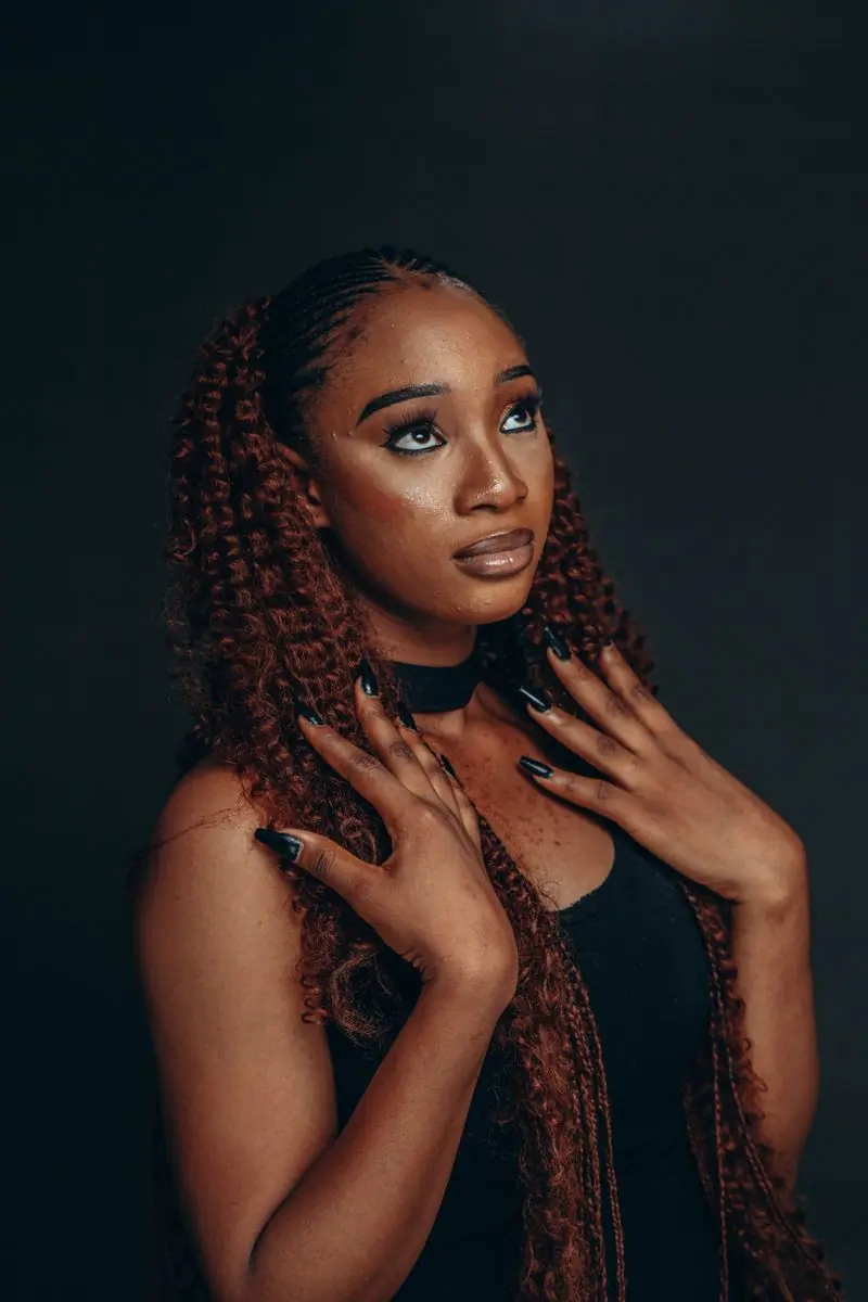 A portrait of a woman with curly hair against a dark ground