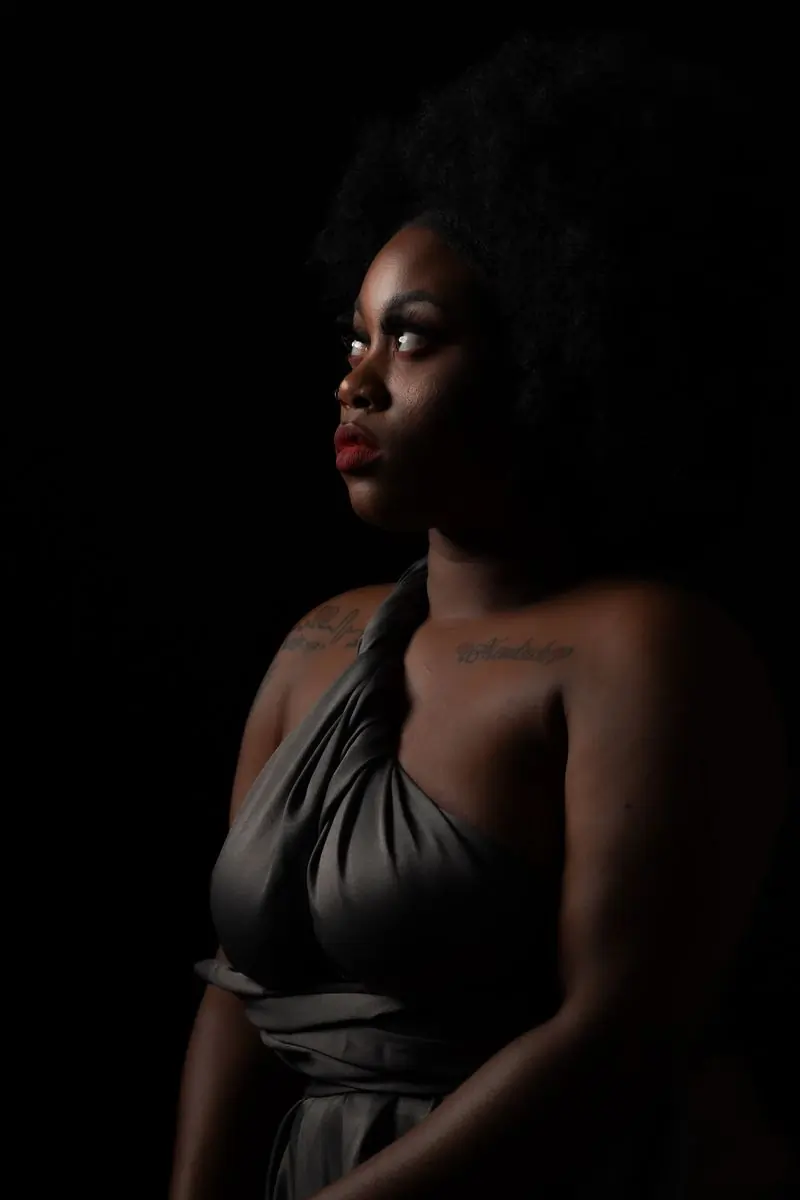 A portrait of a woman lit dramatically against a dark ground