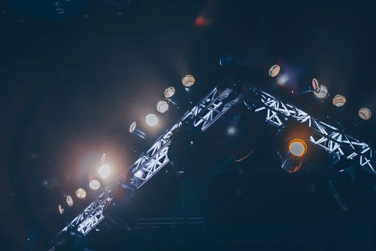 A truss of stage lights burning against a dark ceiling