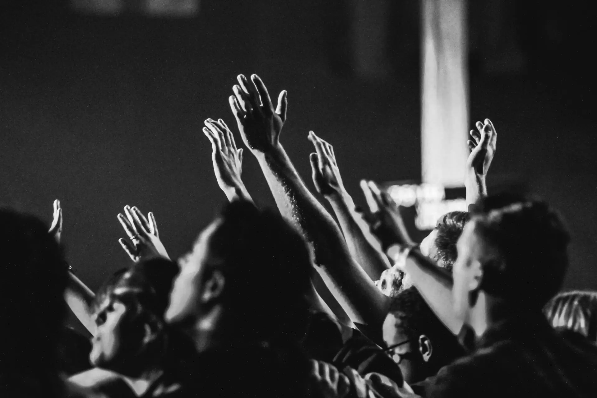A crowd at a night concert with their hands raised above their heads