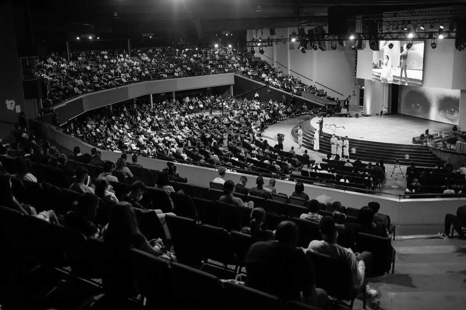 A full auditorium photographed in black and white from the back of the room