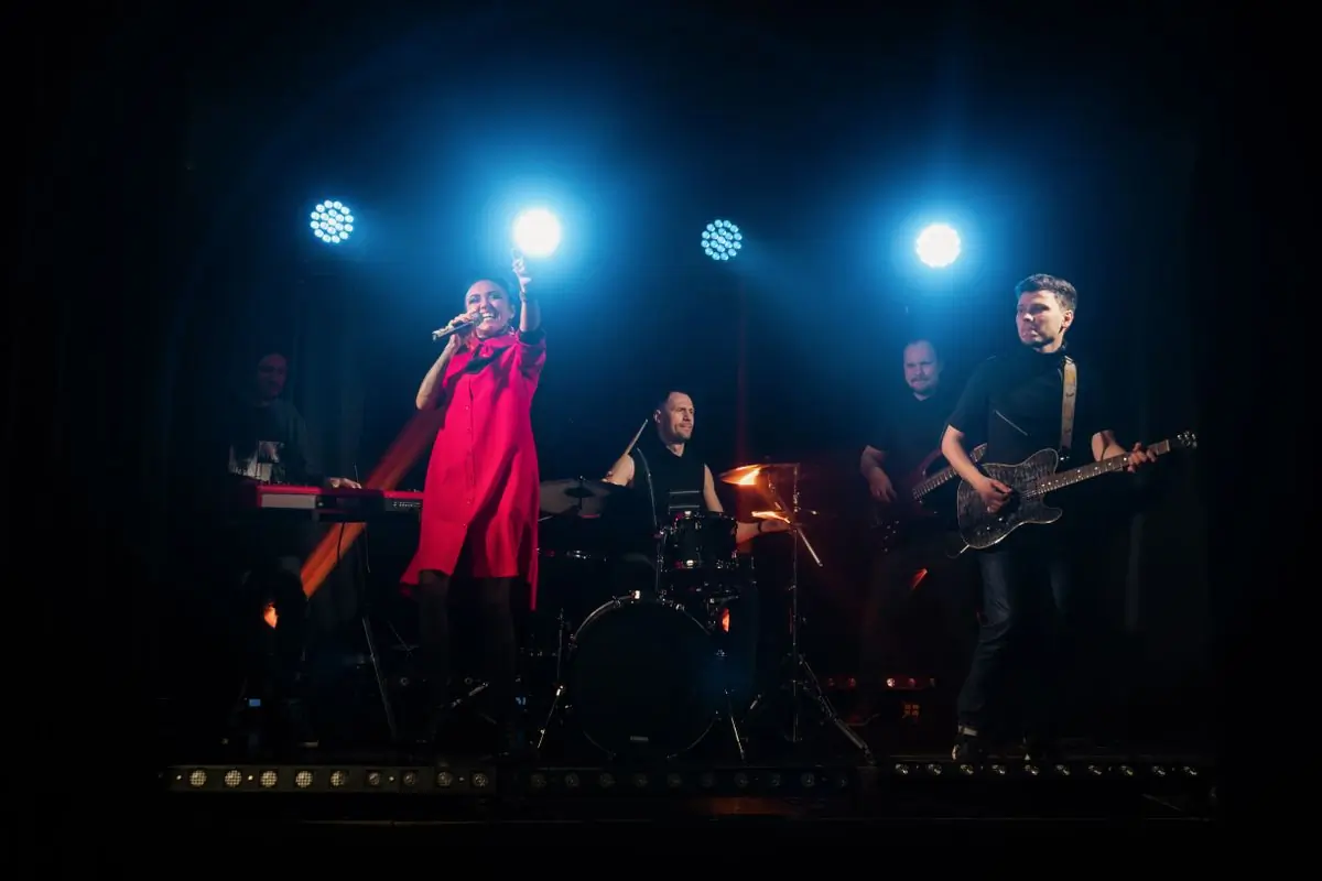 A band performing on stage under red and blue lighting