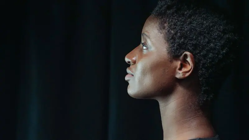 A woman with natural hair photographed in profile against a dark ground