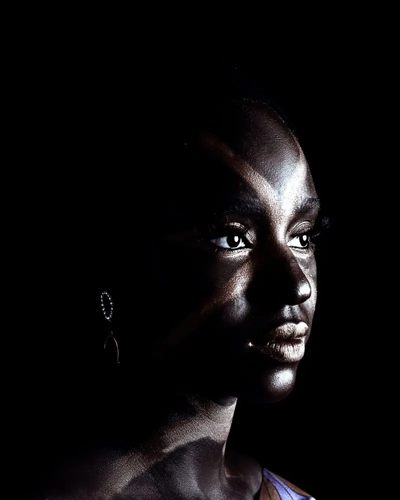 A woman lit from one side against a black ground