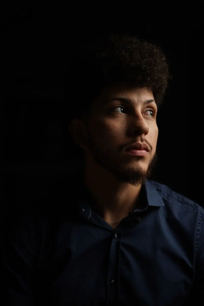 A man with an afro looking towards a single light source
