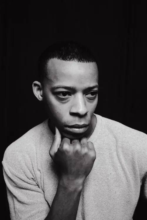 A monochrome portrait of a man with his hand at his chin