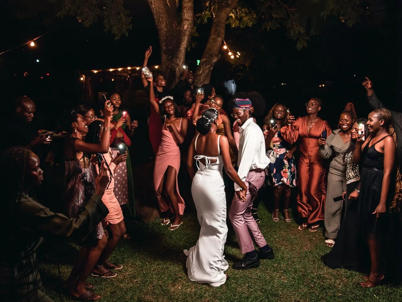Guests in evening dress celebrating around a couple at a garden reception