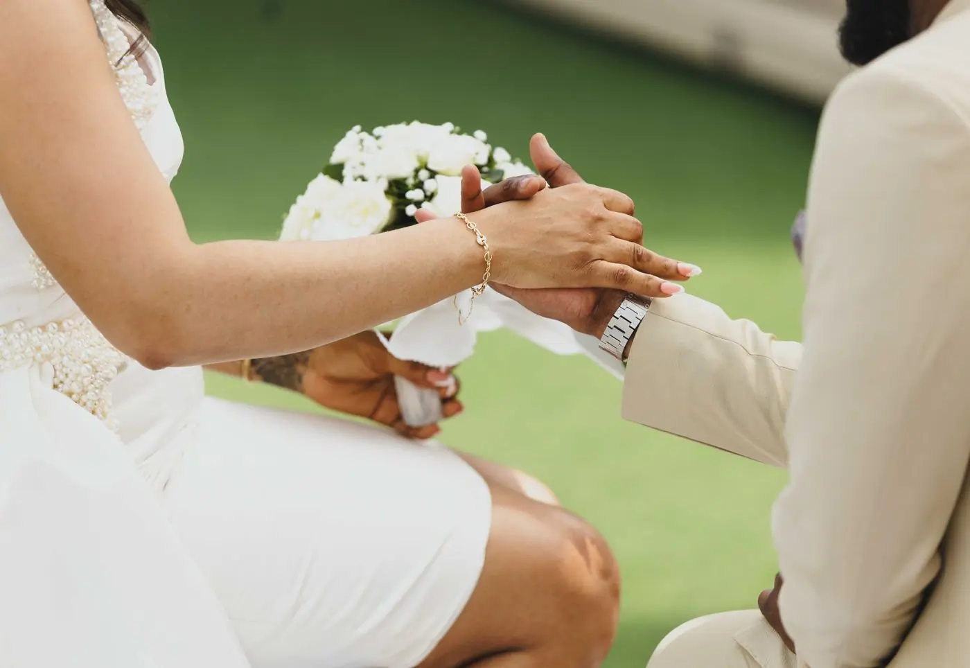 A ring being placed on a bride's finger during an outdoor ceremony