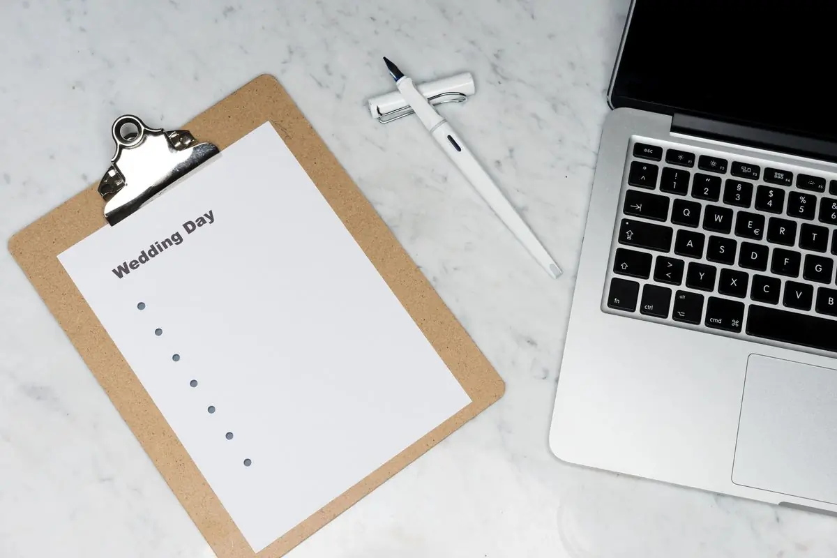 A blank checklist on a clipboard beside a laptop