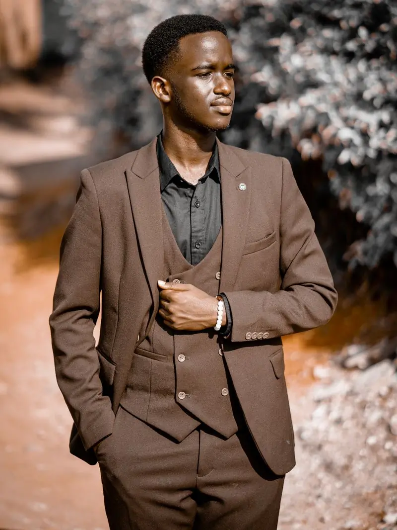A man in a brown three-piece suit standing outdoors