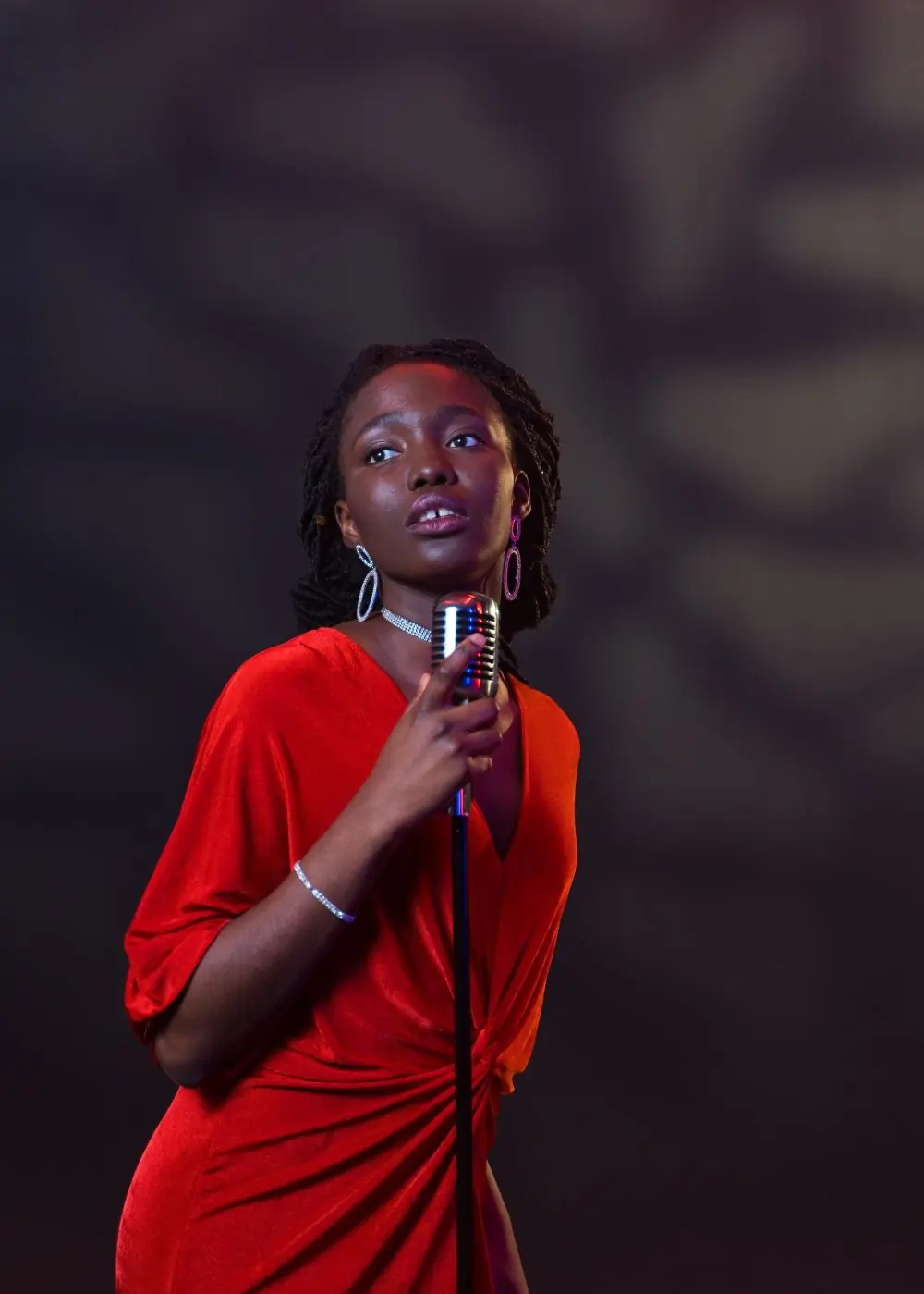 A portrait of the artist looking up, holding a chrome microphone