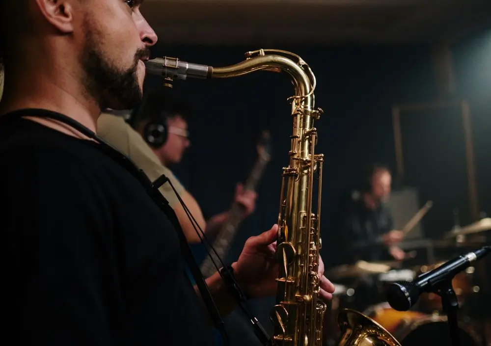 A saxophonist playing with the rest of the band behind him in low light