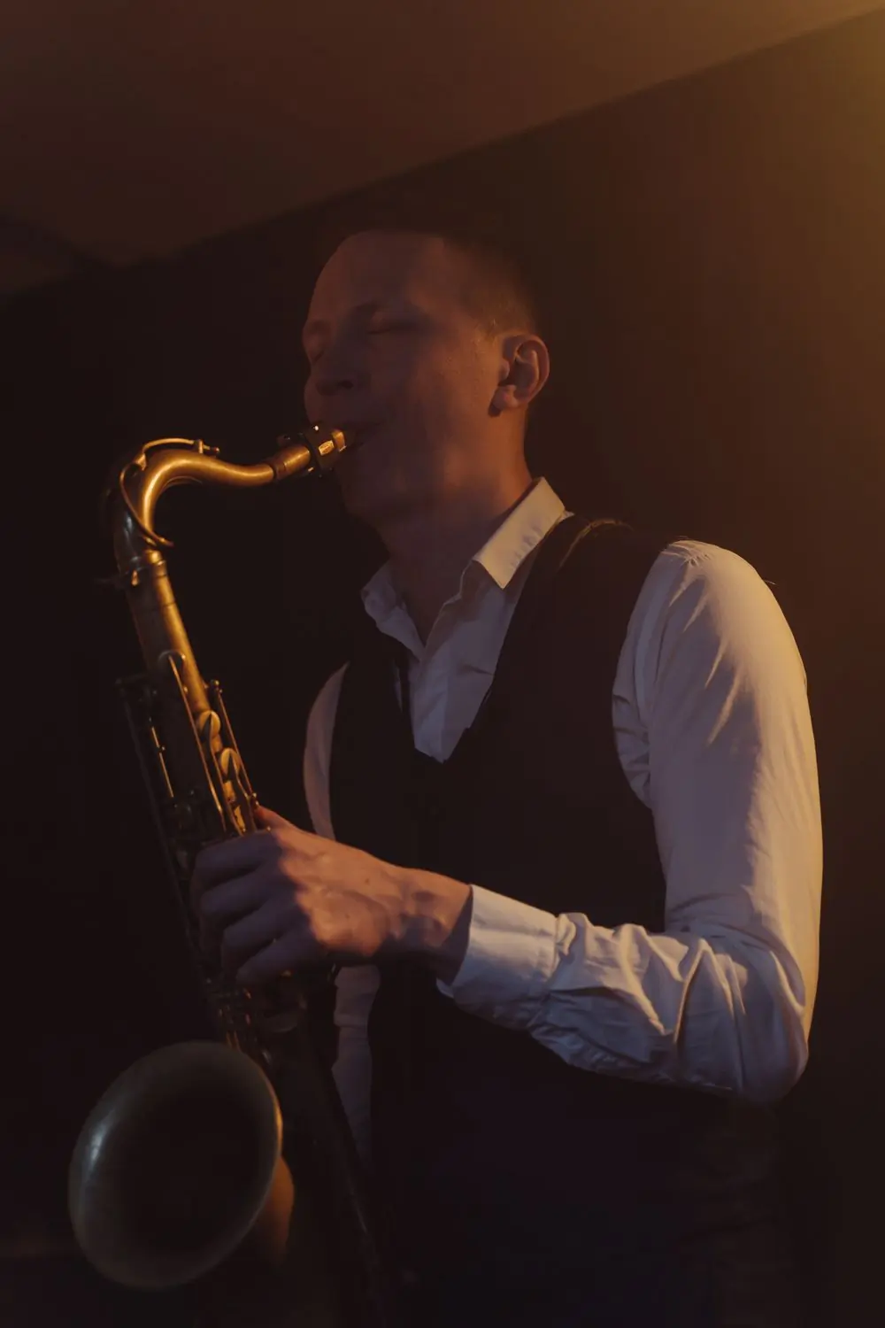 A saxophonist playing in a dimly lit jazz venue