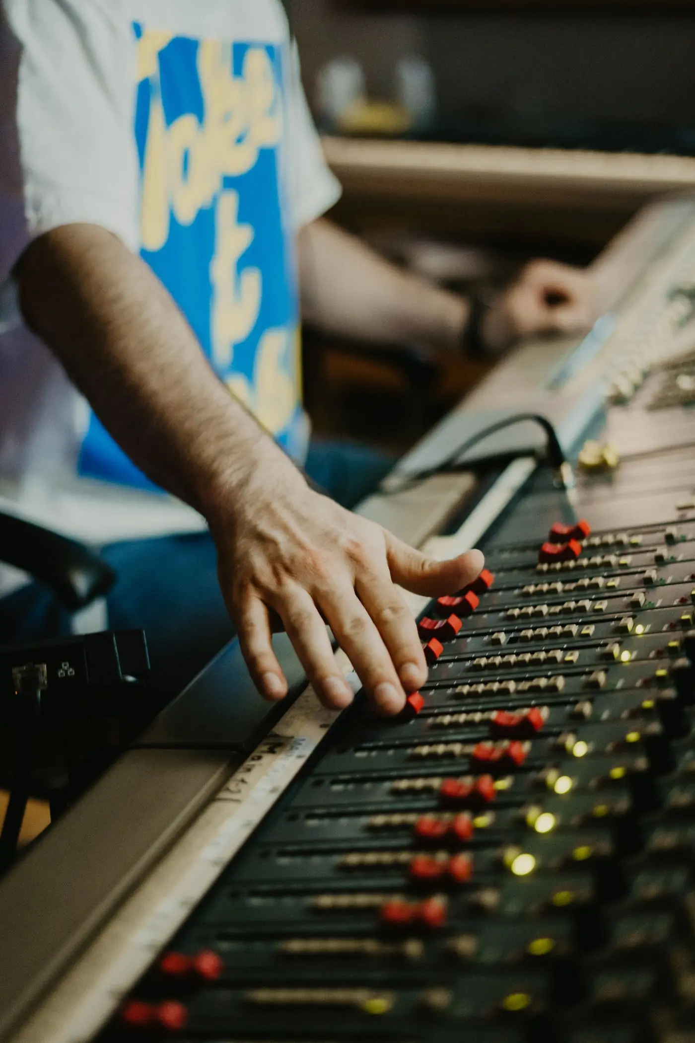 A sound engineer's hands working the faders of a mixing console